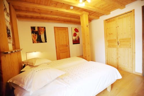 Dormitorio rústico de madera luminoso en Le ValOmbré en Saint-Pierre-de-Chartreuse con vigas de madera vista, ropa de cama blanca y pino