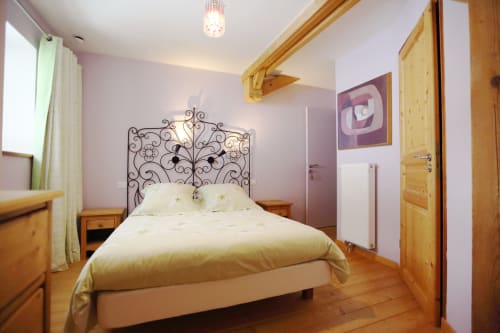 Dormitorio Grand ValOmbre con cabecera de hierro forjado ornamentado, muebles de madera y vistas a las montañas