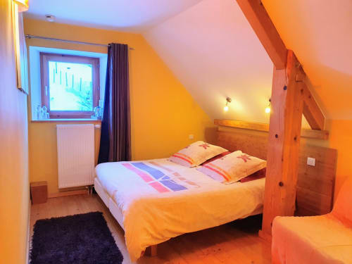 Dormitorio acogedor en la casa rural Le Grand ValOmbre de Le ValOmbré, Saint-Pierre-de-Chartreuse, con paredes amarillas y vigas de madera
