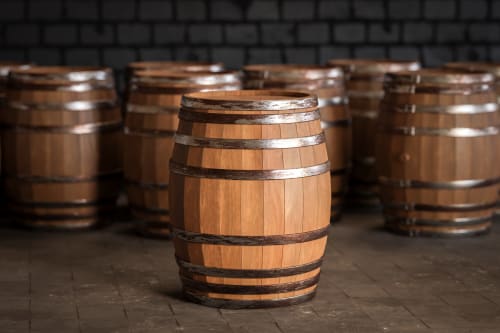 Fûts de vin en bois cerclés de métal dans la cave du château de Mons Boubert, un gîte français.