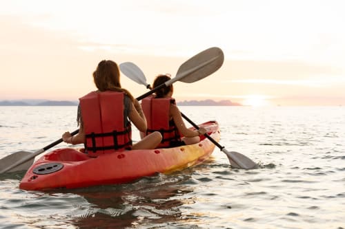 Deux personnes font du kayak au coucher de soleil près de Mons-Boubert, portant des gilets de sauvetage rouges