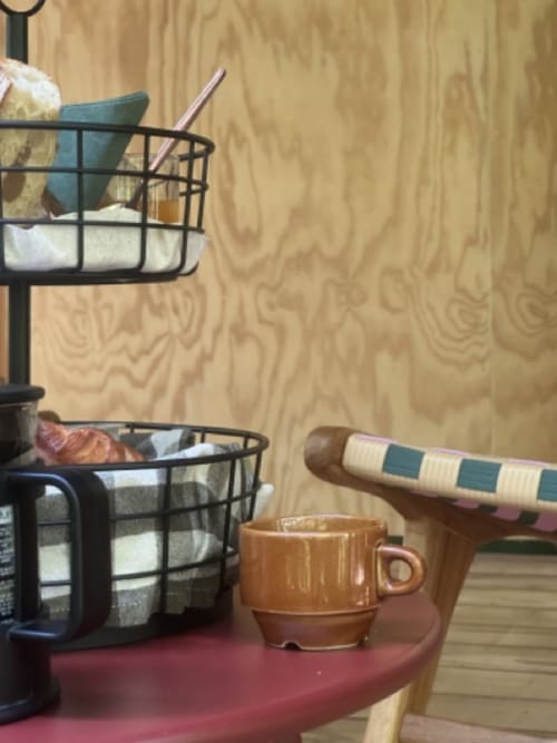 Espace de travail Micro Palaces cosy à Vaulx avec bureau en bois, tasse marron, paniers de rangement et papier peint beige chaleureux