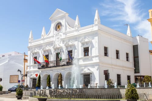 Hotel Plaza Chica en Cartaya, España - edificio colonial blanco con torre de reloj y fuente