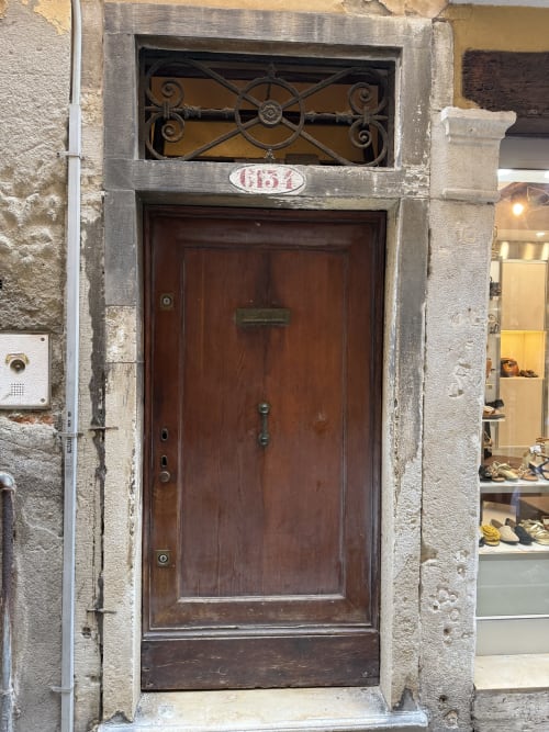 Dark wooden entrance door with decorative ironwork transom window at Luxury Loft Venice, numbered 654, in historic Venice