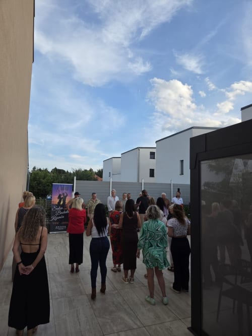 Outdoor courtyard gathering at Hôtel-Restaurant le S'Y in Seingbouse with guests mingling under blue sky