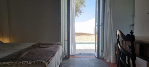Quarto luminoso em Monte Falperras com portas de vidro abertas com vista para os jardins em Mourão, Portugal