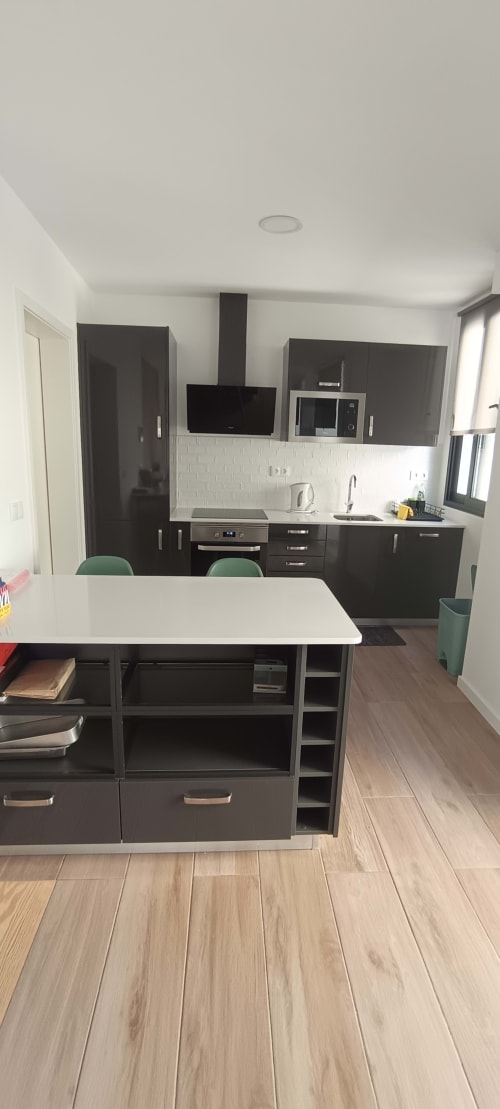 Modern kitchen with black cabinets, white backtile, and dining island at Pés Verdes Hostel, Ponta Delgada