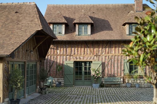 Cour de la Ferme de La Roquerie avec bâtisse à colombages, volets verts et terrasse en pierre à Bonneville-la-Louvet