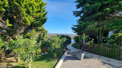 Caminho do jardim com oliveiras e plantas em vasos no hotel rural SELÃO DA EIRA no Alentejo, Portugal, com vista para a montanha