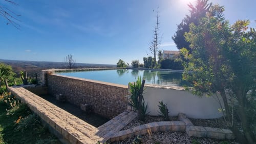 Piscina de água salgada na pousada rural SELÃO DA EIRA no Alentejo, Portugal, com muros de pedra e vistas para as montanhas