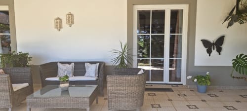 Pátio coberto com móveis de vime, plantas em vaso e portas de vidro no hotel rural SELÃO DA EIRA em Portugal