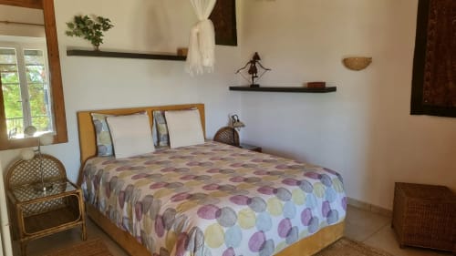 Quarto do hotel rural SELÃO DA EIRA no Alentejo, Portugal com cama de madeira, roupa de cama estampada colorida e vista para a piscina.