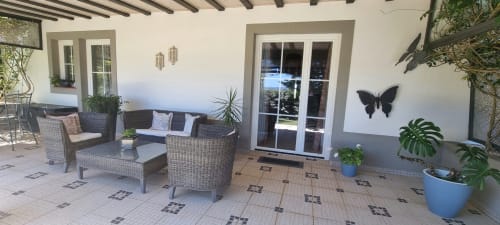 Pátio ao ar livre do hotel rural SELÃO DA EIRA com móveis de vime, plantas em vasos e portas de vidro com vista para a piscina