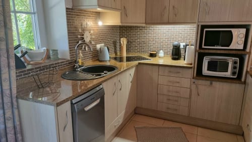 Cozinha moderna com armários de madeira, bancadas de granito, painel de tijolos e eletrodomésticos em aço inoxidável na Casa Peixe