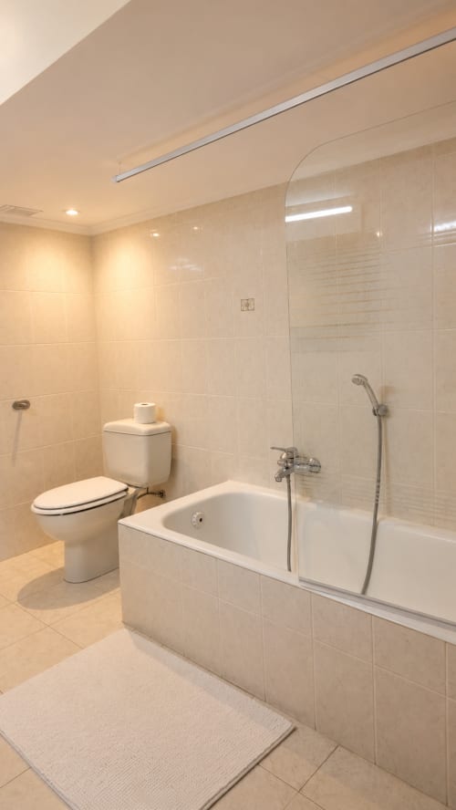 Baño moderno con bañera, ducha, inodoro y paredes de azulejos beige en el hotel rural Matzuri Nekazalturismoa de Mutriku