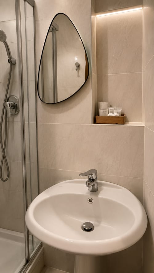 Baño moderno en MATZURI NEKAZALTURISMOA con lavabo redondo blanco, espejo arqueado y ducha en Mutriku