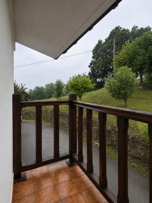 Balcón con barandilla de madera con vistas a la ladera verde y el arroyo en Matzuri Nekazalturismoa, Mutriku