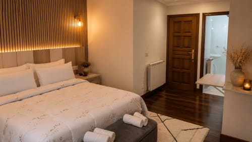 Habitación moderna del hotel MATZURI en Mutriku con cama matrimonial, suelo de madera y vistas a las montañas desde el balcón