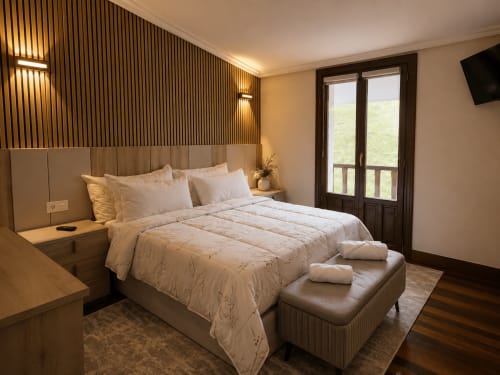 Dormitorio moderno en Matzuri Agroturismo de Mutriku con vistas a la montaña, televisor de pantalla plana y acceso a balcón