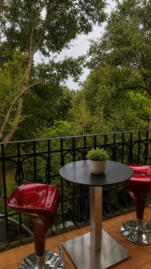 Balcón moderno con sillas rojas con vistas a frondoso bosque en el agroturismo Matzuri de Mutriku