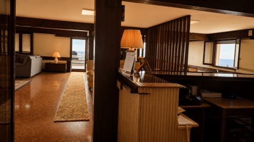 Recepción del hotel Matzuri Nekazalturismoa con mostrador de madera, iluminación cálida y vistas al océano en Mutriku