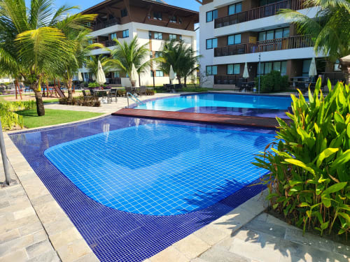 Duas piscinas no resort boutique Labedi Apartamentos em Porto de Galinhas com palmeiras tropicais e design moderno branco