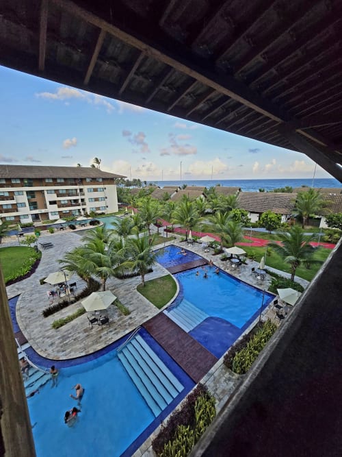 Vista aérea do Labedi Apartamentos com piscinas azuis, palmeiras, oceano e acomodações à beira-mar em Porto de Galinhas