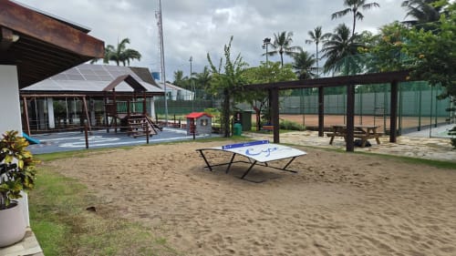 Área de recreação na praia Labedi Apartamentos com mesa de pingue-pongue, quadra de areia e coqueiros em Porto de Galinhas