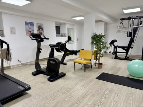 Salle de fitness moderne à l'Auberge Ti'gousket Guingamp avec vélos d'exercice, équipements de musculation et ballon de fitness