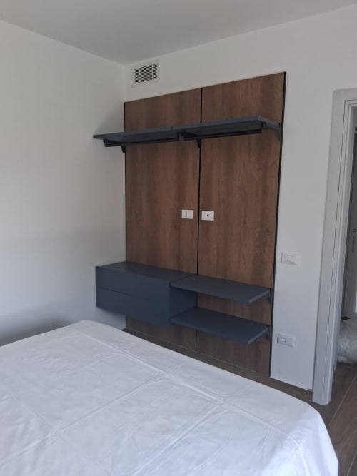 Guardaroba moderno della suite Holiday Suites Pesaro con pannelli in legno scuro e scaffali neri