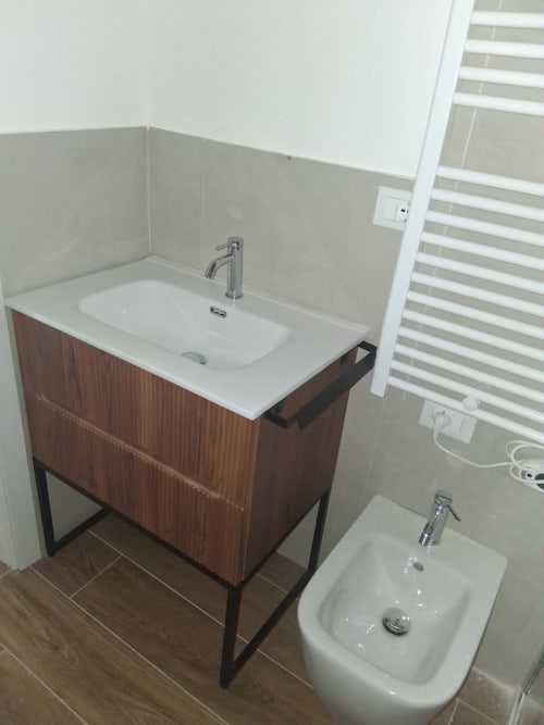 Bagno moderno di Holiday Suites Pesaro con vanity in legno, lavabo bianco e bidet con vista sulla città