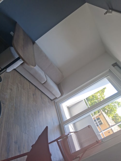 Elegante suite dell'Hotel Holiday Suites Pesaro con divano crema, pavimenti in legno e balcone con vista sulla vegetazione