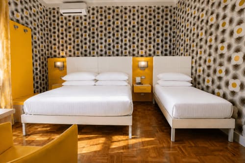 Moderna camera tripla al B&B Pellicano di Reggio Calabria con due letti, dettagli gialli, carta da parati decorativa e legno