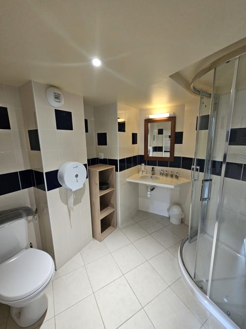 Salle de bains moderne à l'Auberge Du Campcardos avec carrelage noir et blanc, douche, lavabo et toilettes à Porta