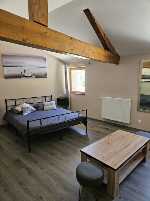Suite moderne à l'Auberge Du Campcardos à Porta avec poutres en bois, vue montagne et mobilier confortable.