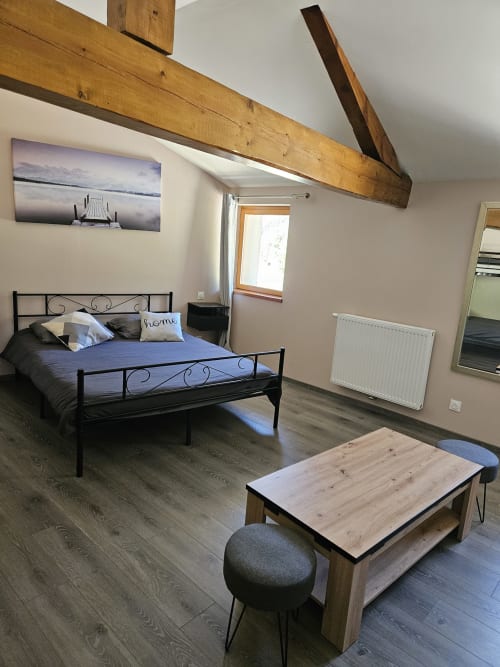 Suite chambre moderne à l'Auberge Du Campcardos, Porta, avec poutres en bois, lit en métal, literie bleue et table basse en bois