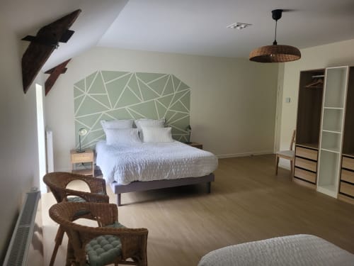 Spacious bedroom at Le Clos de la Touche with geometric headboard, wicker chairs, and modern amenities in Cheillé