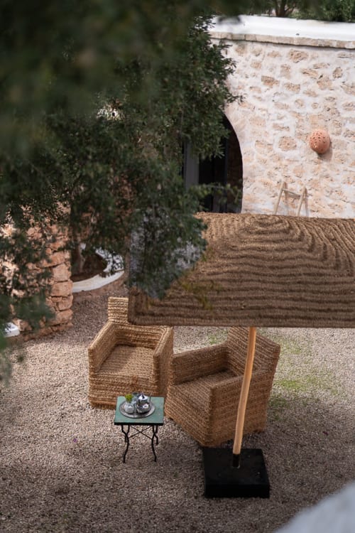 Rustic courtyard seating area at Domaine Belhazar in Essaouira with woven chairs and stone buildings