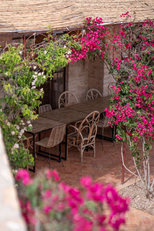 Charming courtyard dining area at Domaine Belhazar in Essaouira with vibrant magenta bougainvillea flowers framing wooden