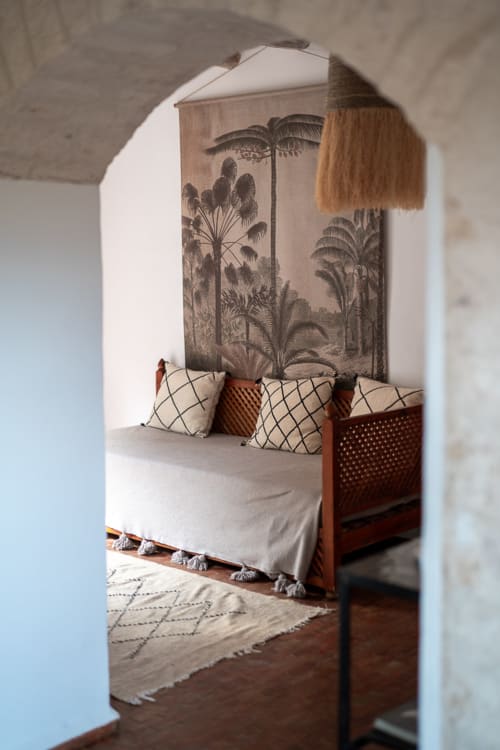 Luxurious bedroom at Domaine Belhazar in Essaouira with canopied bed, tropical palm wall art, and Moroccan décor