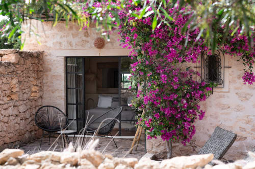 Charming terrace at Domaine Belhazar in Essaouira with vibrant magenta bougainvillea, black chairs, and stone walls