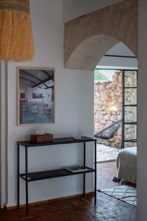 Modern entryway at Domaine Belhazar in Essaouira with black console table, framed art, and archway leading to terrace view