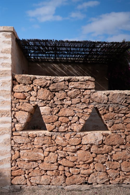 Traditional stone building at Domaine Belhazar in Essaouira with rustic arched window and woven roof structure
