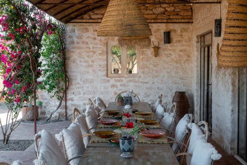 Rustic outdoor dining patio at Domaine Belhazar in Essaouira with magenta bougainvillea, stone walls, and set table