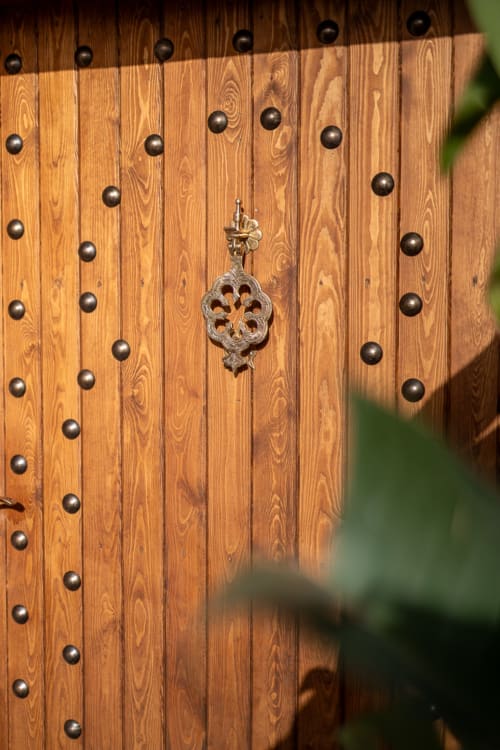 Ornate wooden door with decorative metal studs and intricate knocker at Domaine Belhazar, Essaouira