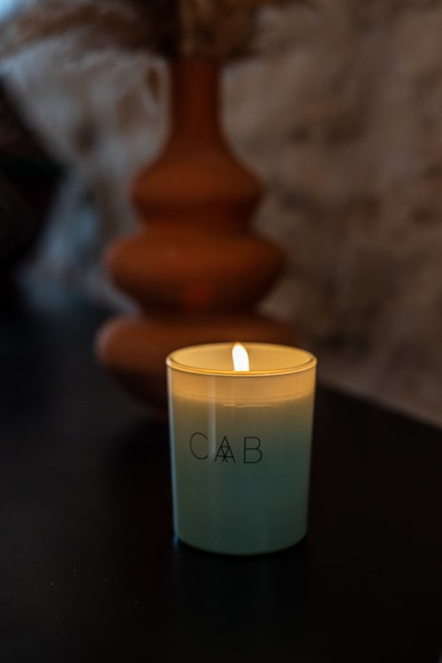Lit CAB scented candle with gradient packaging at Domaine Belhazar boutique hotel in Essaouira, Morocco