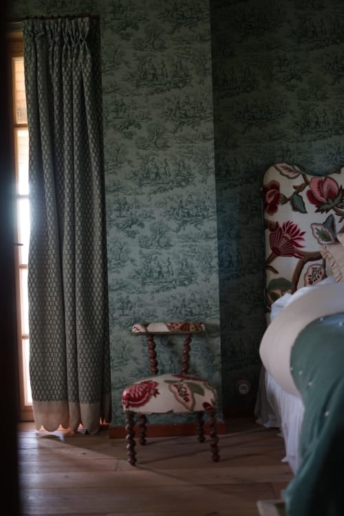 La chambre Pond Room de la Ferme La Roquerie avec papier peint vert toile de Jouy, fauteuil fleuri et fenêtre vue sur le lac