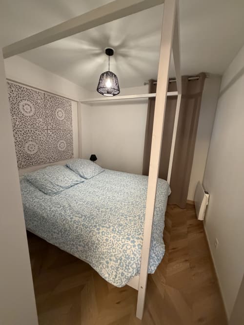 Lit à baldaquin douillet dans l'appartement Appart'NoOm avec tête de lit motifs et luminaires suspendus