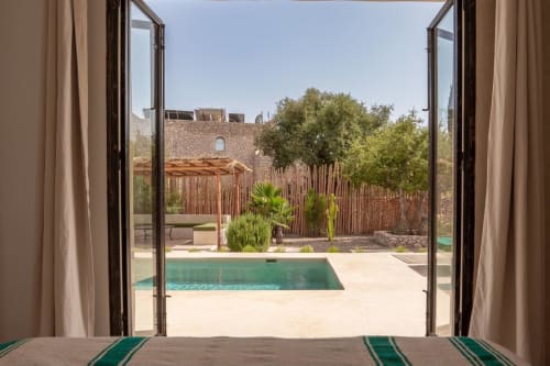 Vue depuis une chambre du Domaine Belhazar à Essaouira : piscine turquoise, patio et cour traditionnelle de riad avec palmiers