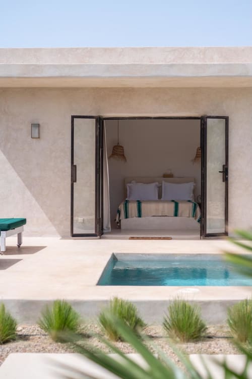 Pavillon chambre Domaine Belhazar à Essaouira, portes ouvertes, vue sur piscine, design minimaliste côtier